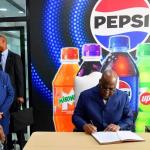 Le chef de l'État signant le livre d'or de la société PEPSI 