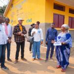 Photo de Guylain Nyembo et la délégation de CFEF au Kongo-Central, auprès d'un bâtiment  de PDL145T