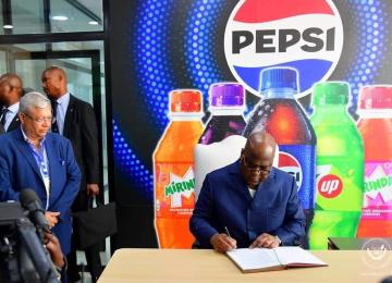 Le chef de l'État signant le livre d'or de la société PEPSI 