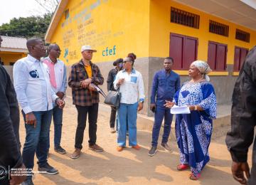 Photo de Guylain Nyembo et la délégation de CFEF au Kongo-Central, auprès d'un bâtiment  de PDL145T