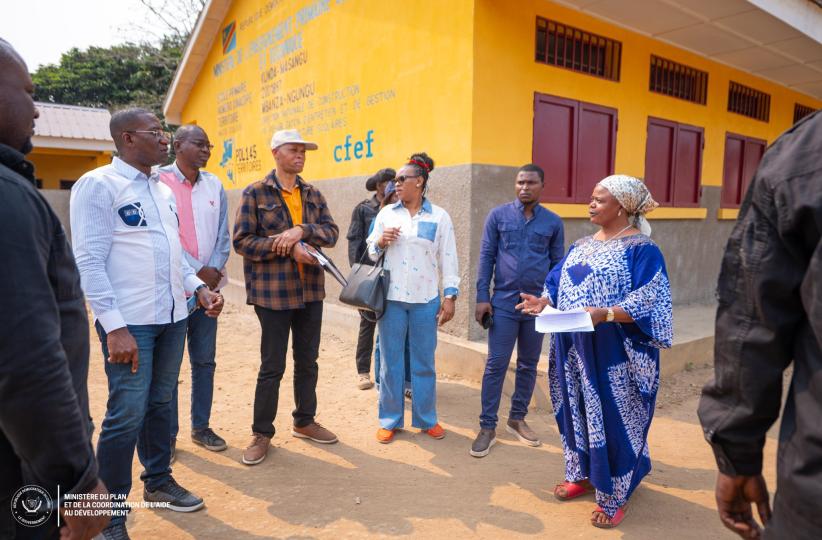 Photo de Guylain Nyembo et la délégation de CFEF au Kongo-Central, auprès d'un bâtiment  de PDL145T